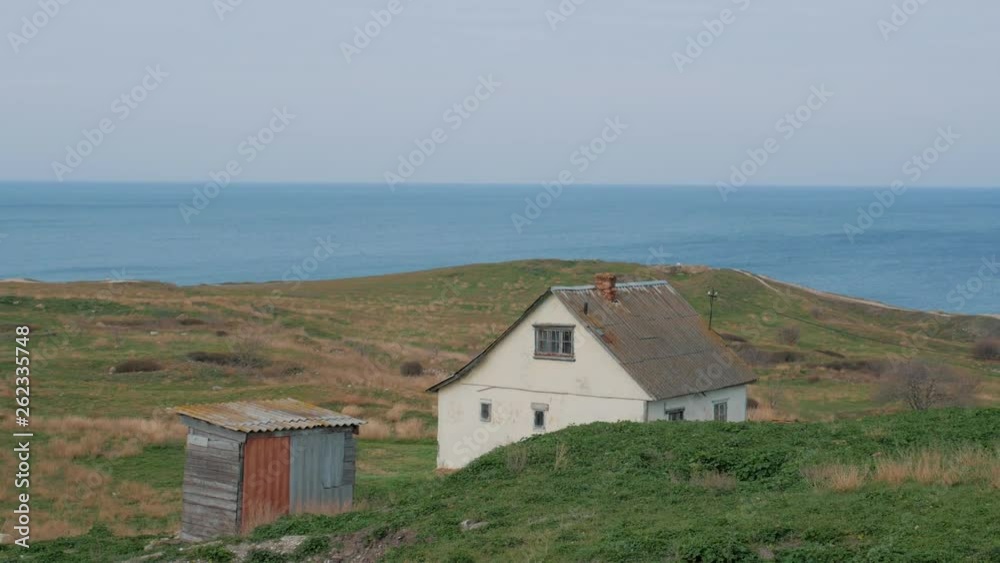 Old white house on hills with green grass on sea coast