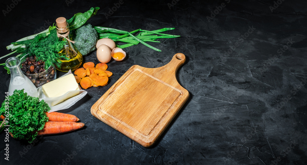 Natural products rich in vitamin A as parsley leaves, dried apricots, carrots, broccoli, butter, milk, egg yolk. Dark background, top view Natural products rich in vitamin A as parsley leaves, dried apricots, carrots, broccoli, butter, milk, egg yolk. Dark background, top view