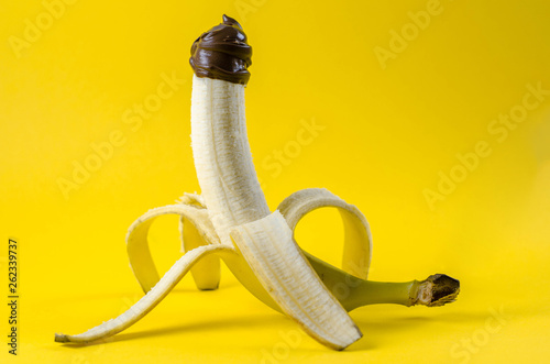 Banana covered with chocolate sauce on color yellow background. Sex concept. Erotic Fruit