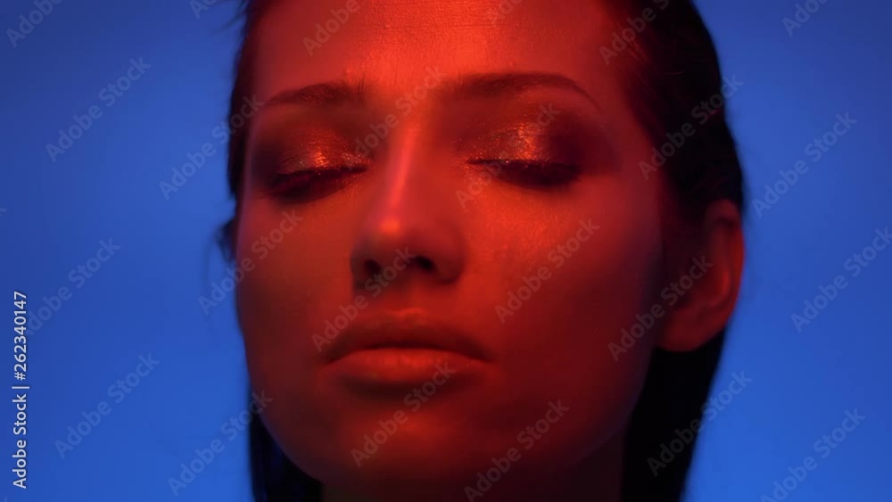 Close-up shoot of fashion model in red and blue neon lights watching upwards and closing eyes in satisfaction. Close-up shoot of fashion model in red and blue neon lights watching upwards and closing eyes in satisfaction.