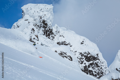 Skier spraying soft powdery snow among volcanic peak in the backcountry near Niseko, Japan.