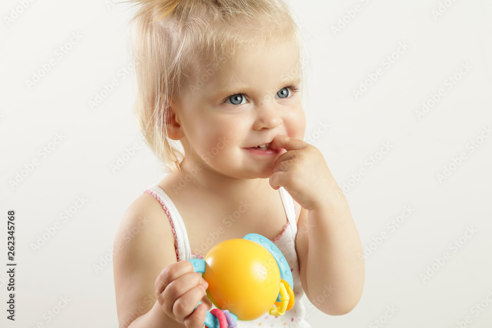 Studio portrait of an adorable blonde smiling baby girl showing her teeth with a finger Studio portrait of an adorable blonde smiling baby girl showing her teeth with a finger