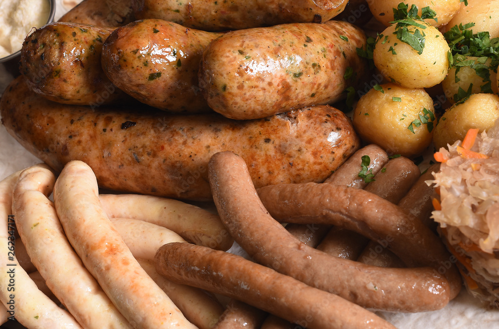 Beer snacks plate, red, white and yellow sauces on silver dish. Sausage assortment with with young potatoes, fried cabbage on white background isolated on white background. Close up of beer snacks set Beer snacks plate, red, white and yellow sauces on silver dish. Sausage assortment with with young potatoes, fried cabbage on white background isolated on white background. Close up of beer snacks set