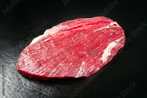 Raw dry aged wagyu flank steak as closeup on black background with copy space