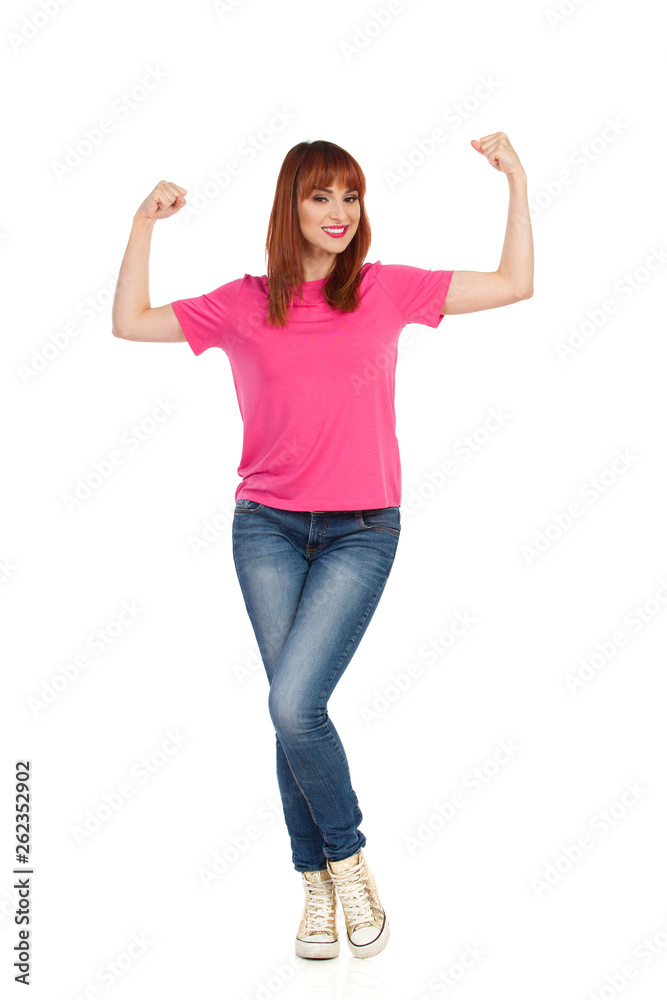 Smiling Young Woman Is Flexing Muscles And Looking At Camera Smiling Young Woman Is Flexing Muscles And Looking At Camera