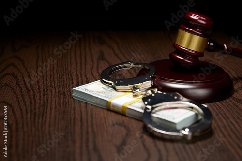 HANDCUFFS, GAVEL AND STACK OF MONEY ON WOOD