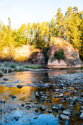 beautiful golden sunrise over forest river with sandstone cliffs on the shores