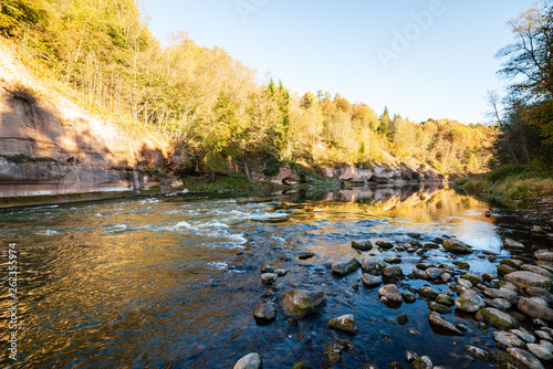 beautiful golden sunrise over forest river with sandstone cliffs on the shores