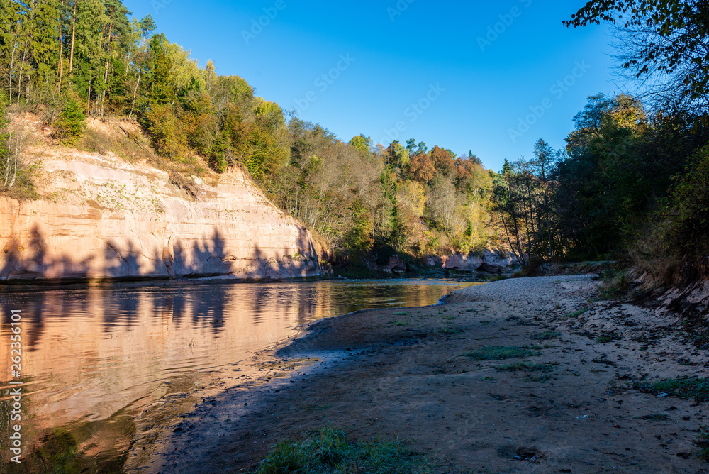 beautiful golden sunrise over forest river with sandstone cliffs on the shores