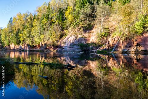 beautiful golden sunrise over forest river with sandstone cliffs on the shores