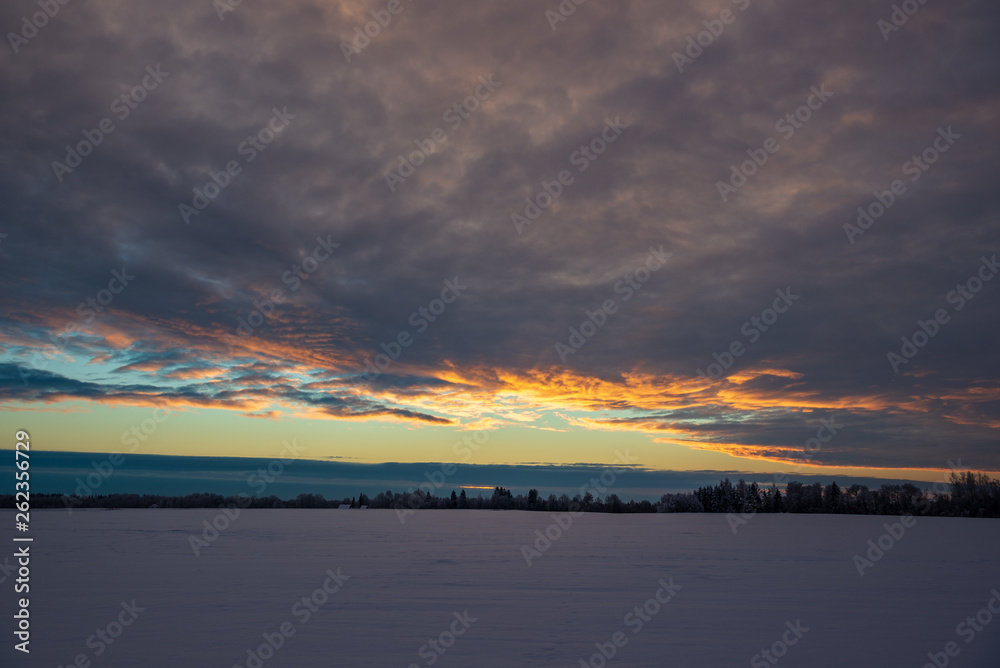 colorful sunset light over fields of snow in winter