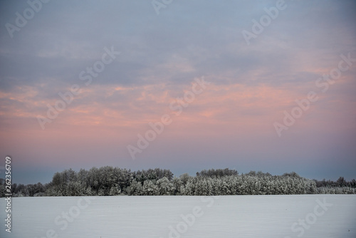 colorful sunset light over fields of snow in winter