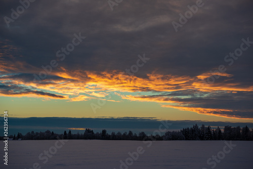 colorful sunset light over fields of snow in winter