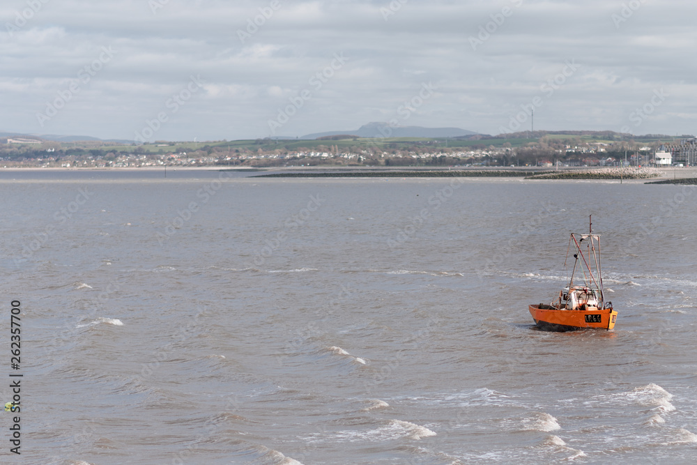 A small little fishing boat is rocked by the waves and windy weather in Morecambe Bay - Winter 2019
