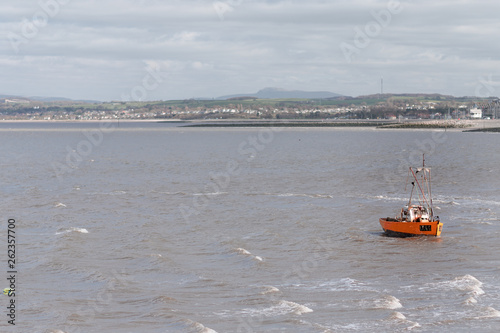 A small little fishing boat is rocked by the waves and windy weather in Morecambe Bay - Winter 2019