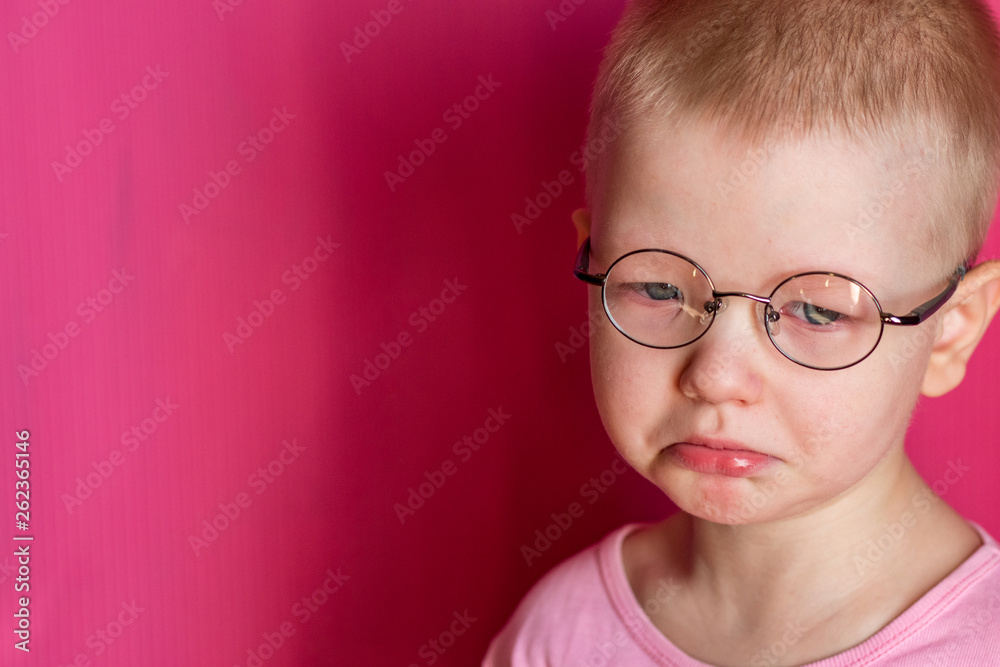 Happy blond child posing in room over pink background. Kid takes off and puts on glasses for fitting Happy blond child posing in room over pink background. Kid takes off and puts on glasses for fitting