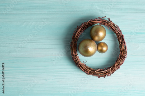 golden eggs in the nest over wooden background with copy text
