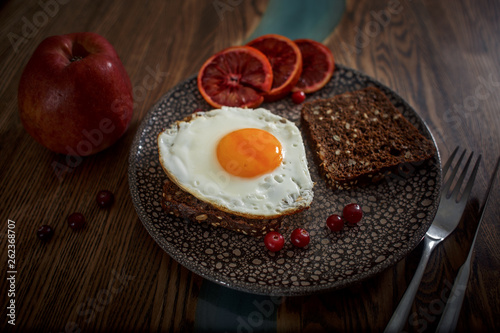 Grain bread with fried egg, tomato, cheese and bacon on ceramic plate with red orange  photo