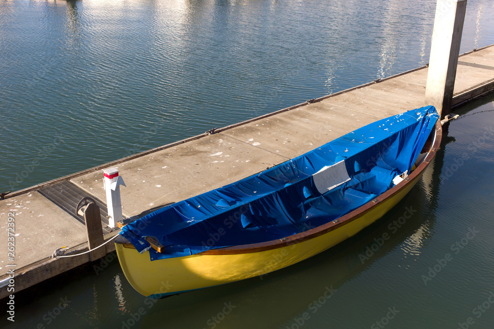blue and yellow rowboat by a pier on the bay in harbor