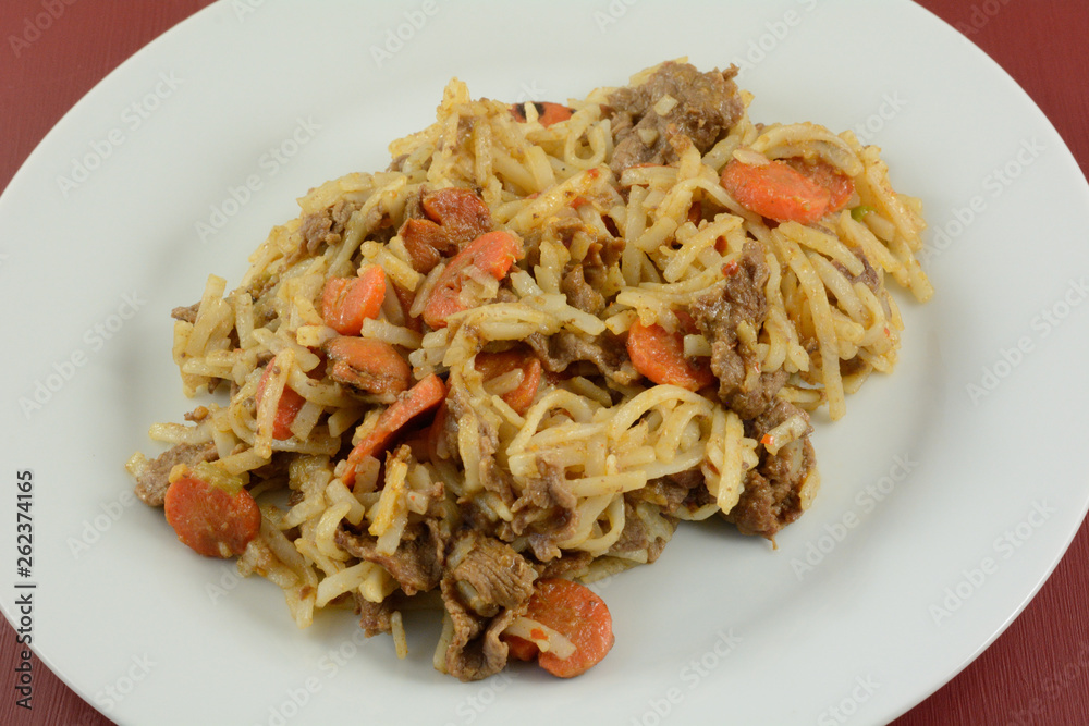 Sliced beef and carrots with rice noodles and sauce on white plate