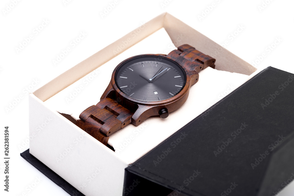 wooden wrist watch with a bracelet and a round dial packed in a cardboard box, an accessory in a package on a white background. wooden wrist watch with a bracelet and a round dial packed in a cardboard box, an accessory in a package on a white background.