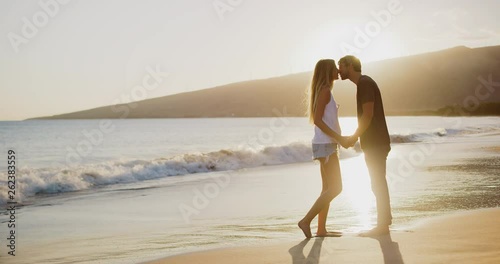 Young attractive couple kissing on the beach at sunset in slow motion, summer romance photo