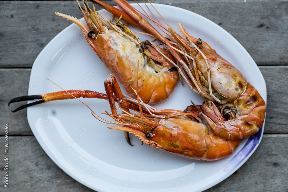 Closeup grilled shrimps on the white plate put on wood background in restaurant Ayutthaya, Thailand seafood Closeup grilled shrimps on the white plate put on wood background in restaurant Ayutthaya, Thailand seafood