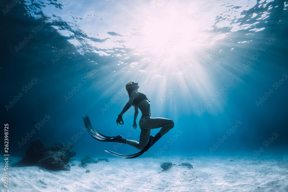 Woman freediver over sandy sea with fins. Freediving in blue ocean