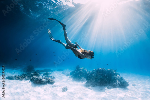 Fototapeta Woman freediver glides with fins