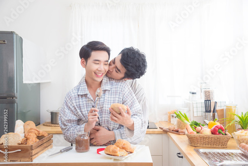Canvas Print Young asian male homosexual couple wearing pajamas having beakfast in kitchen