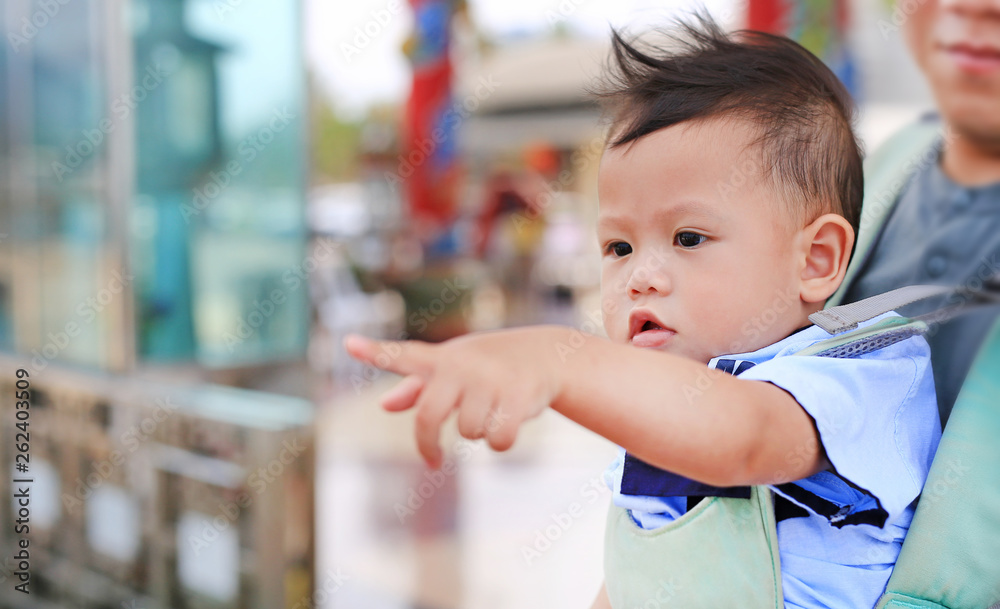 Adorable little baby boy pointing something with father carry by hipseat outdoor. Close up. Adorable little baby boy pointing something with father carry by hipseat outdoor. Close up.