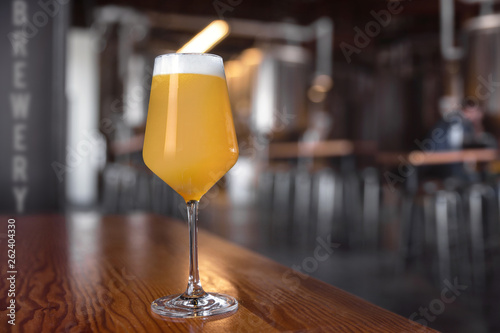Fresh unfiltered craft beer IPA in stemmed glassware, on counter of microbrewery photo