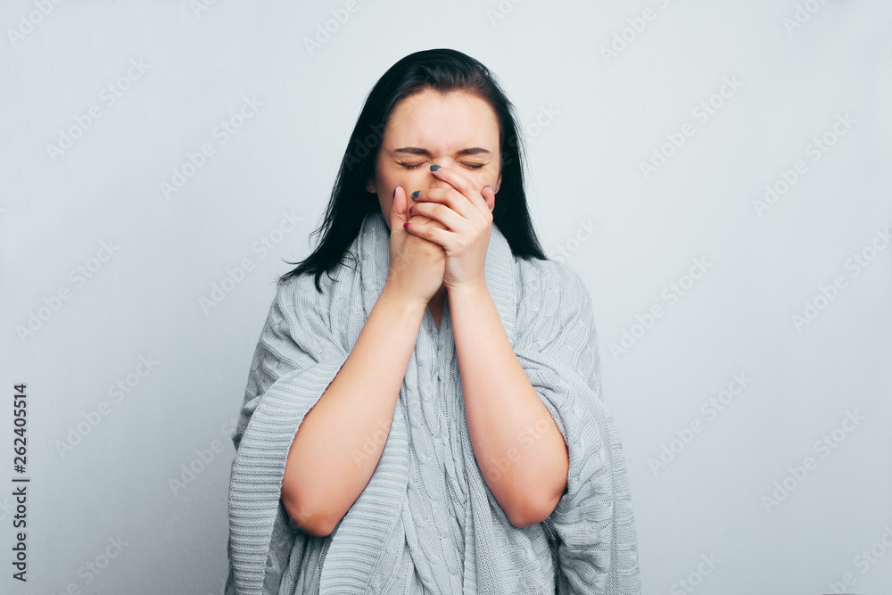 Beautiful brunette girl covers her mouth with her hands sneezing from allergies, colds, flu. Beautiful brunette girl covers her mouth with her hands sneezing from allergies, colds, flu.