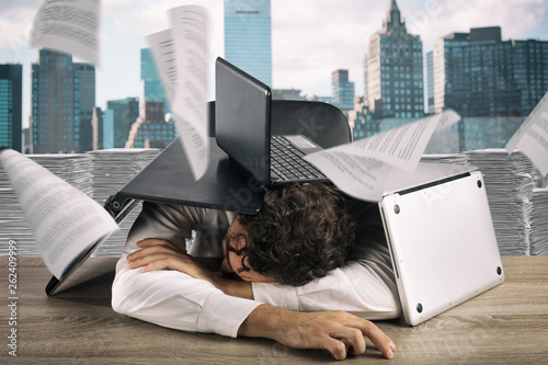 Slika na platnu Tired businessman sleeping under a pile of laptops due to workload