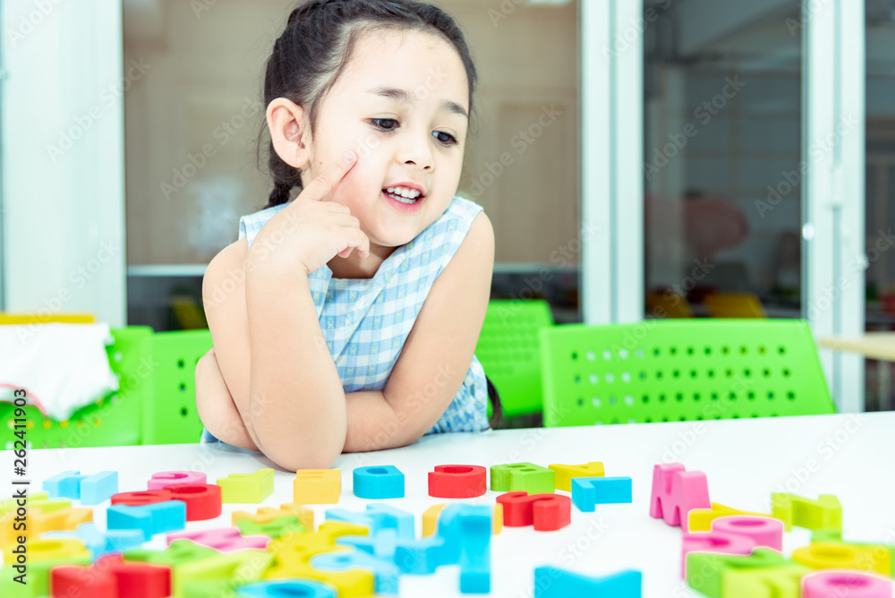 Cute kids female playing with toy designer on the floor at home. Child girl exciting while playing with alphabet colorful blocks. Kindergarten educational games for determination, intention concept Cute kids female playing with toy designer on the floor at home. Child girl exciting while playing with alphabet colorful blocks. Kindergarten educational games for determination, intention concept