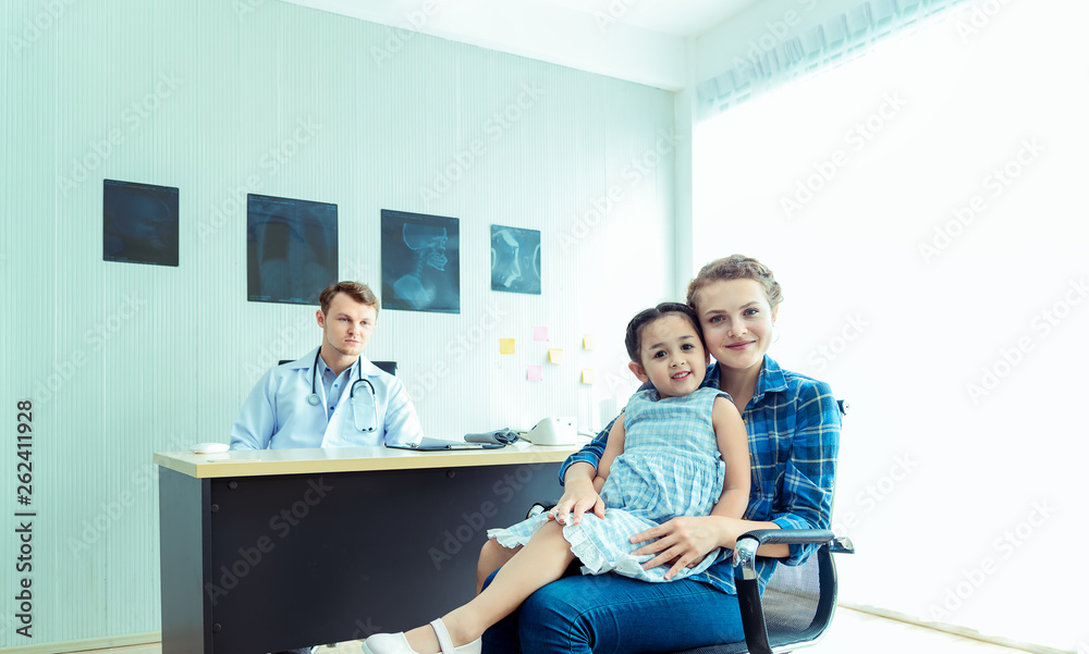 Young friendly caucasian pediatrician doctor is examining child patient girl with her mother ,consultation with a stethoscope and tablet pc in clinic office .Healthcare and medical kid concept Young friendly caucasian pediatrician doctor is examining child patient girl with her mother ,consultation with a stethoscope and tablet pc in clinic office .Healthcare and medical kid concept
