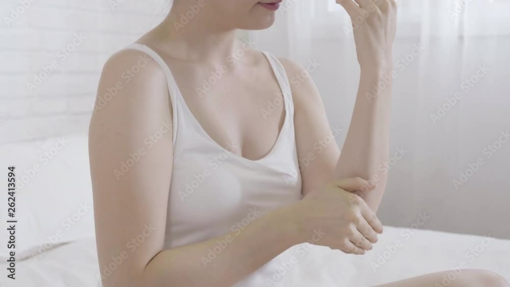 slow motion closeup on asian woman hands applying moisturizing cream. young elegant lady smiling sitting in white bed in bedroom putting massage body skin by lotion in the morning after wake up. slow motion closeup on asian woman hands applying moisturizing cream. young elegant lady smiling sitting in white bed in bedroom putting massage body skin by lotion in the morning after wake up.