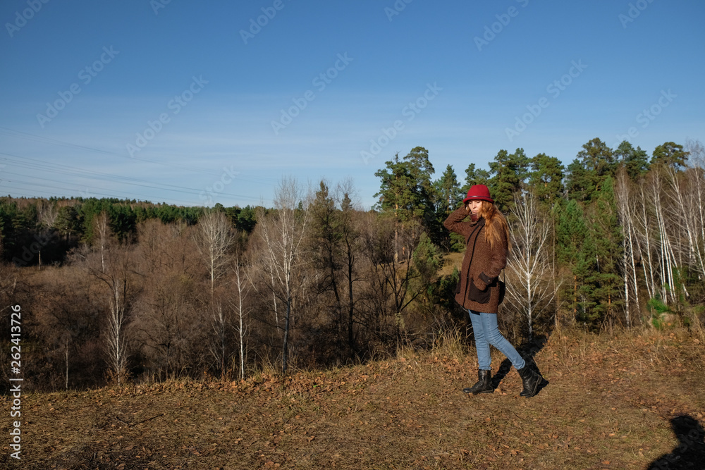 Female model in a red hat and autumn coat in the woods for a walk. Female model in a red hat and autumn coat in the woods for a walk.