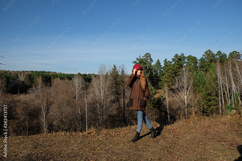 Female model in a red hat and autumn coat in the woods for a walk. Female model in a red hat and autumn coat in the woods for a walk.