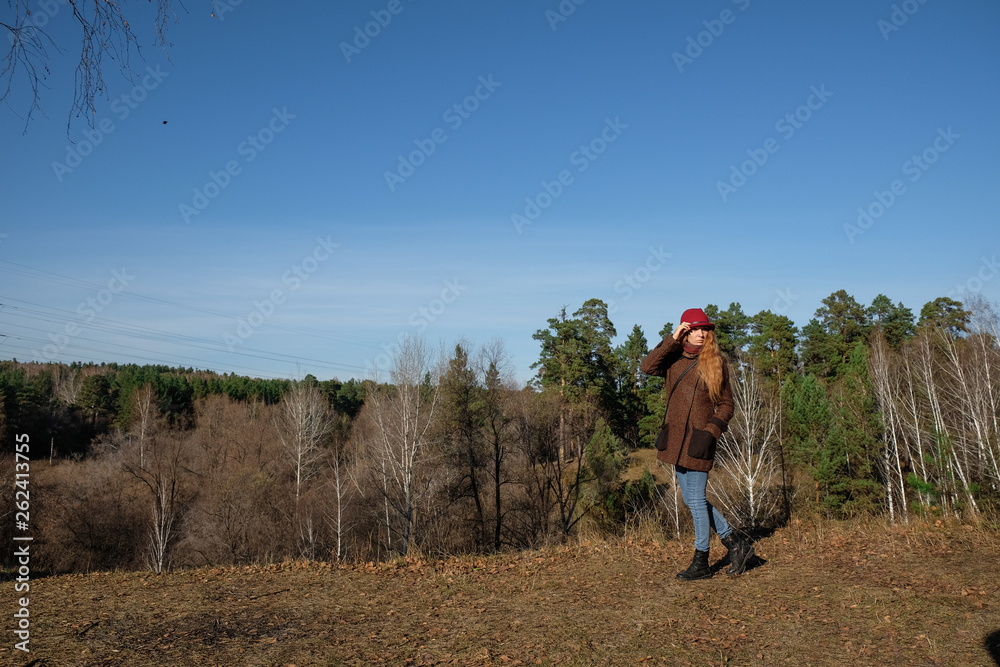 Female model in a red hat and autumn coat in the woods for a walk. Female model in a red hat and autumn coat in the woods for a walk.