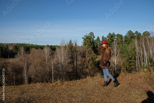 Female model in a red hat and autumn coat in the woods for a walk.
