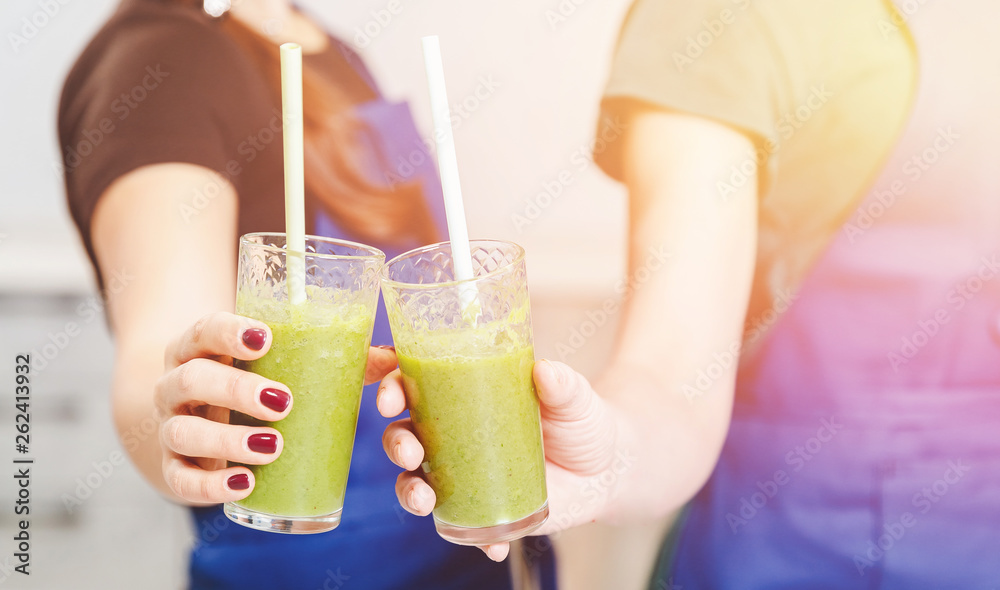 Hands of young girls hold in glasses detox smoothies, green color, close-up Hands of young girls hold in glasses detox smoothies, green color, close-up