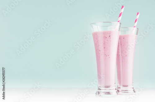 Blueberry smoothies with straws in high glass on white wood table and pastel blue wall, copy space.