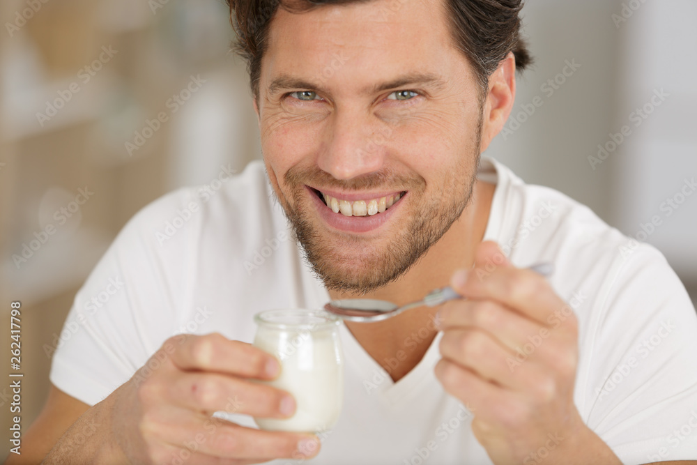 smiling young man eating yogurt smiling young man eating yogurt