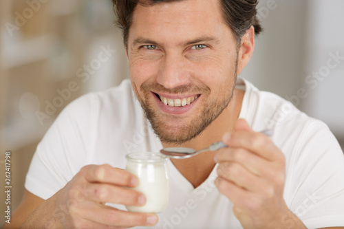 smiling young man eating yogurt