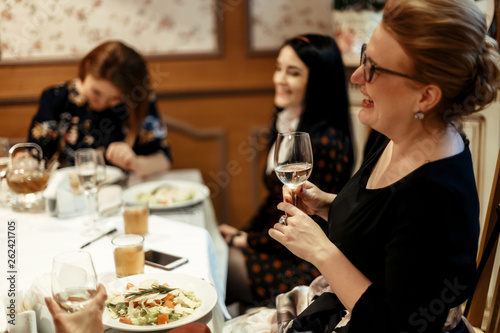 group of luxury elegant women celebrating with champagne and laughing in rich restaurant