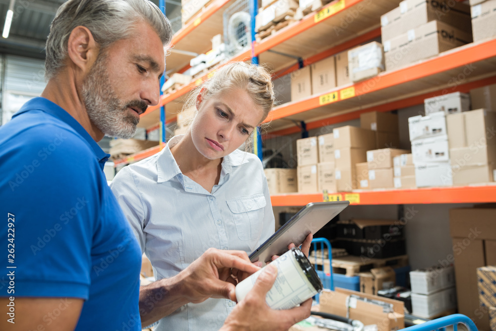 workers in storeroom reading product information
