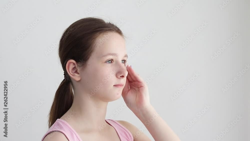 Teenager girl cleans the skin of the face with a cotton swab with lotion. The concept of cleanliness and face care teenage. Teenager girl cleans the skin of the face with a cotton swab with lotion. The concept of cleanliness and face care teenage.