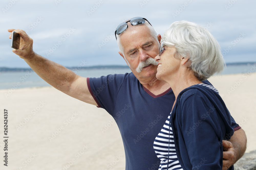 senior couple taking a selfie at the beach senior couple taking a selfie at the beach