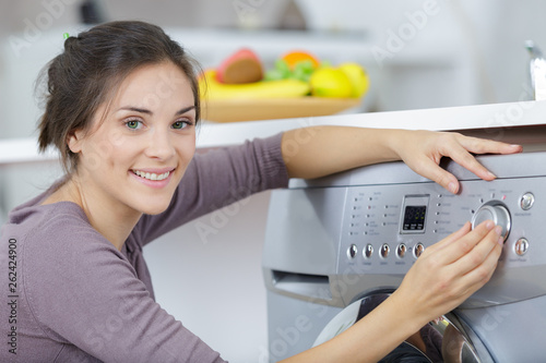 portrait of woman choosing programme on washing machine